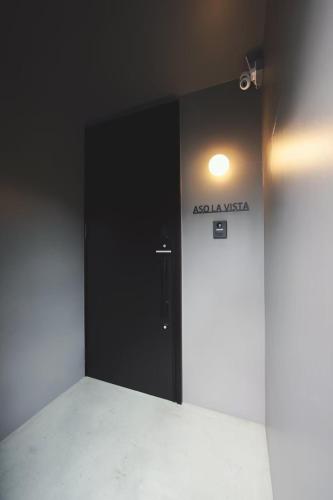 a black door in a room with a sign on the wall at Aso La Vista 阿蘇の家 in Aso