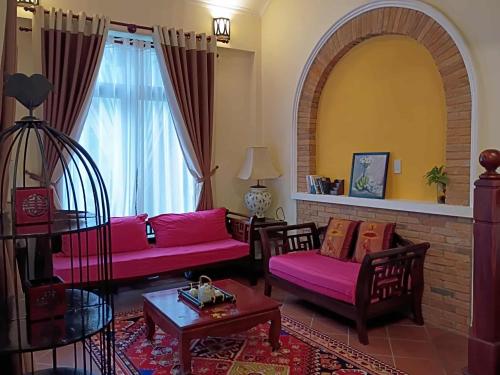 a living room with pink couches and a large window at Mekong Palm House in Can Tho
