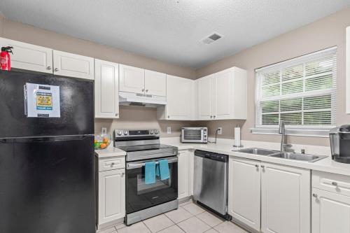 a kitchen with white cabinets and a black refrigerator at Spectacular Quiet Townhome with Modern Comfort in Stockbridge