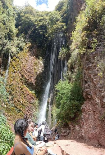 a group of people sitting in front of a waterfall at Casa Tejedora in Chinchero