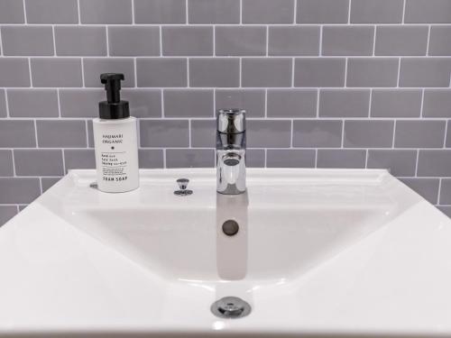a bathroom sink with a bottle of soap and a soap dispenser at Tabist Business Hotel Kawaramachi in Takamatsu