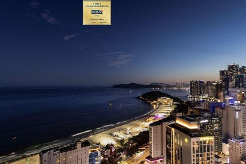 a view of the ocean from a city at night at Marysol by Haeundae beach in Busan