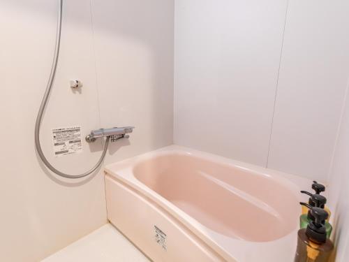 a bath tub in a bathroom with a shower at Tabist Business Hotel Kawaramachi in Takamatsu