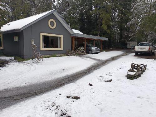 a house with a snow covered driveway in front of it at Cabañas Ladera Sur Melipeuco in Melipeuco