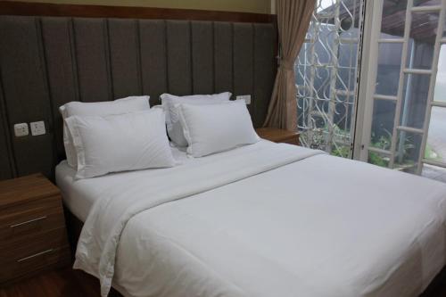 a white bed with white pillows and a window at Diyar Villas Puncak M3/47 in Puncak