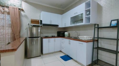 a kitchen with white cabinets and a stainless steel refrigerator at Diyar Villas Puncak M3/47 in Puncak