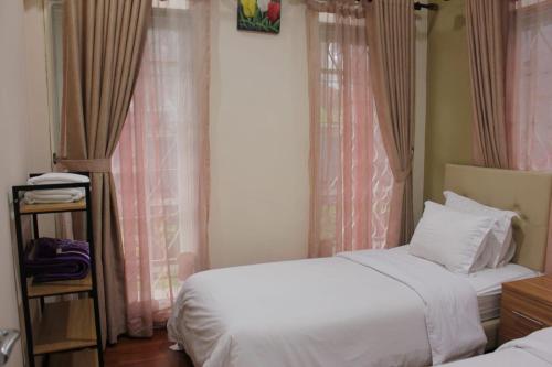 a bedroom with two beds and a window at Diyar Villas Puncak M3/47 in Puncak