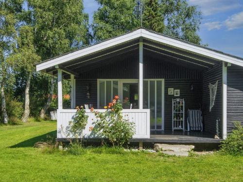 a small black cottage with a porch and a deck at 6 person holiday home in Glesborg in Glesborg
