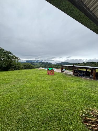 a green yard with a red house in the grass at Casa de campo La Apacheta in Lules