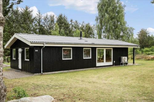 a black house with white windows in a yard at LF15197-Hojslev-Venovej-36 in Højslev