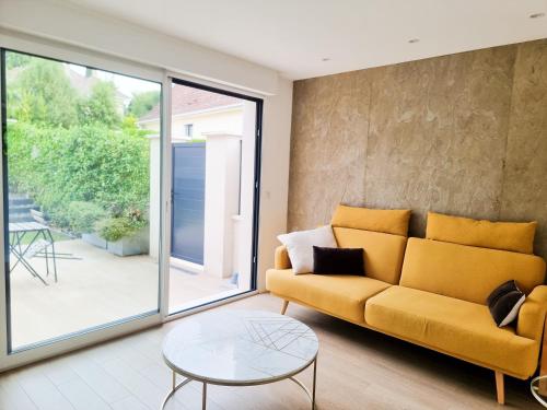 a living room with a yellow couch and a glass table at EXIGEHOME- Maison d'architecte avec SPA - V2 in Orgeval