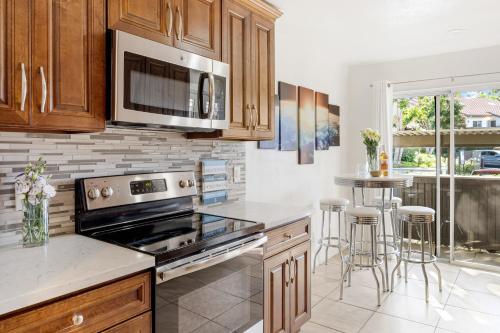 a kitchen with wooden cabinets and a stove top oven at Coastal Retreat w Pool Spa BBQ Near Beaches Golf Courses Ritz Pointe Condo by AvantStay in Dana Point