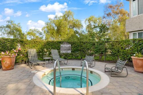 a hot tub in a patio with chairs and a fence at Coastal Retreat w Pool Spa BBQ Near Beaches Golf Courses Ritz Pointe Condo by AvantStay in Dana Point