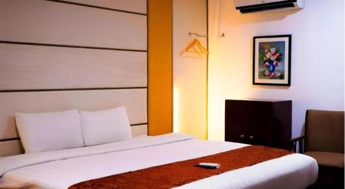 a bedroom with a bed with a remote control on it at Horizon Hotel in Olongapo