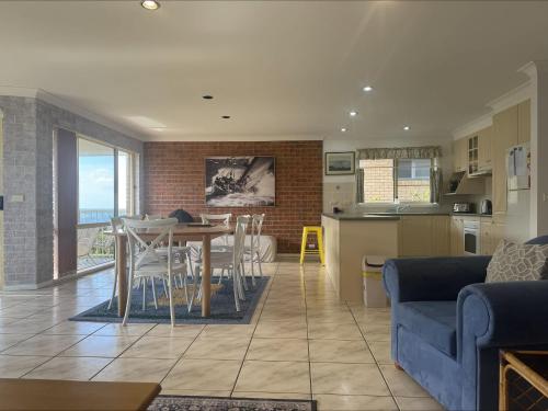 a living room and kitchen with a table and a blue couch at Grand Spindrift - Entire Waterfront House in Malua Bay