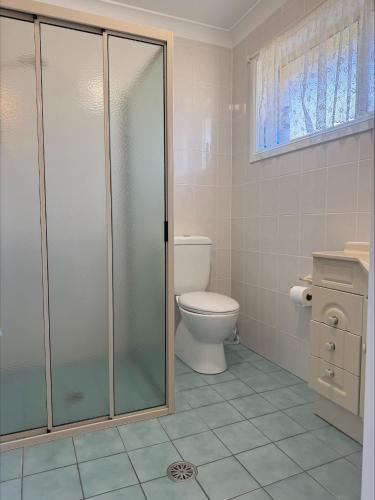 a bathroom with a toilet and a glass shower at Grand Spindrift - Entire Waterfront House in Malua Bay