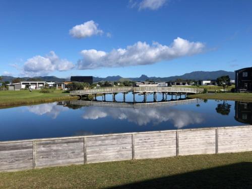 a body of water with a bridge and buildings at Hosts on the Coast Lake View in Matarangi