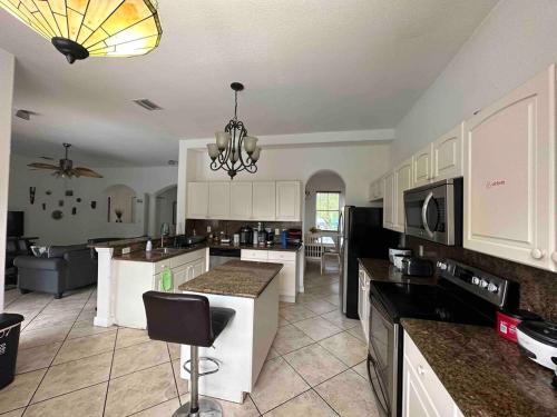a kitchen with white cabinets and black counter tops at The Miami Lakes Pool House in Miami Lakes