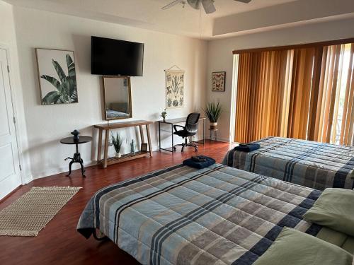 a bedroom with two beds and a flat screen tv at The Miami Lakes Pool House in Miami Lakes