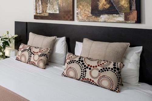 a white bed with pillows and a black headboard at Oaks Ipswich Aspire Suites in Ipswich