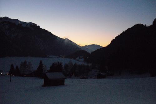 a sunset in the mountains with a snow covered field at Haus Bergwelt in Grän