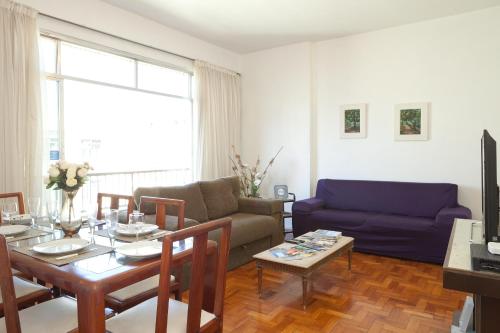 a living room with a table and a blue couch at Apartamento completo na praia de COPACABANA, 3 SUITES , em andar alto com vista mar, ar ,wifi, tv canais a cabo, pauloangerami MVC18 in Rio de Janeiro