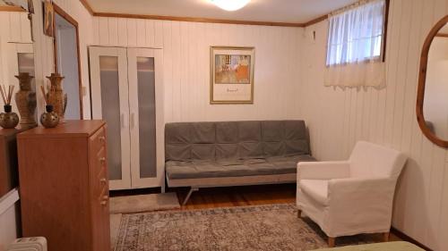 a living room with a couch and a chair at Garsoniera in Leirvåg