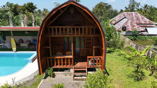 a gazebo by a swimming pool next to a house at Raturinjani homestay in Selong