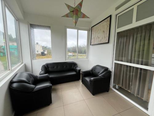 a living room with two leather chairs and windows at Away From Home - 10 - Rooms In Ooty, Home Stay in Ooty in Ooty