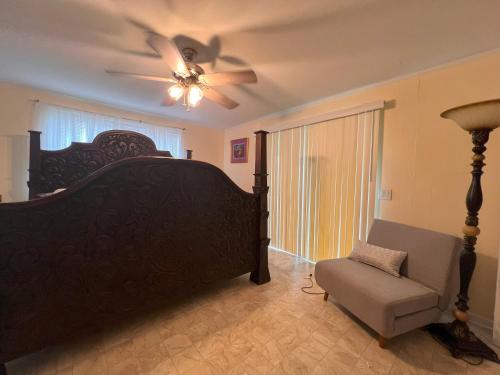 - une chambre avec un lit, un ventilateur de plafond et une chaise dans l'établissement Private Guest Room 5 Min and less from FAMU, FSU, Downtown- TheDollHouse, à Tallahassee