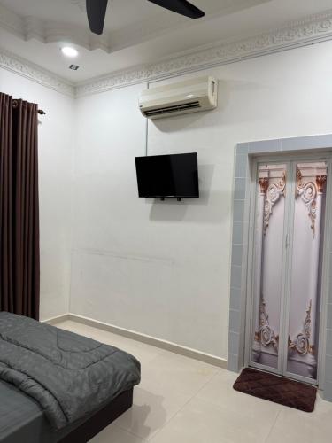 a bedroom with a bed and a tv on the wall at The Lodge in Kuala Kerai