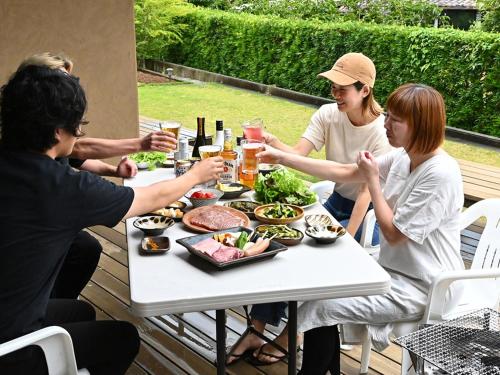 a group of people sitting around a table eating food at 隠れ家アートヴィラ Villa Revolla in Makinohara