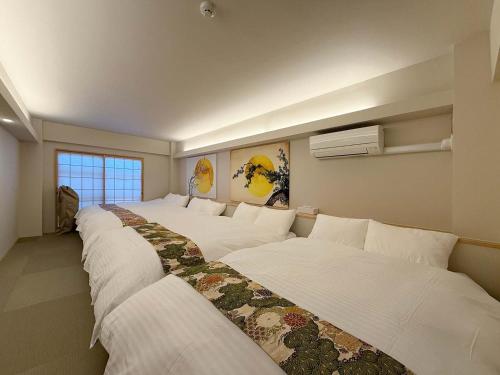 a row of white beds in a room at b hotel Miyajima Omotesando - Sacred Island Stay 21 in Miyajima