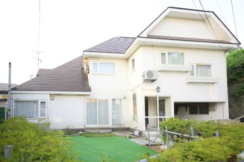 a white house with a lawn in front of it at グッドタイム新城 in Aomori