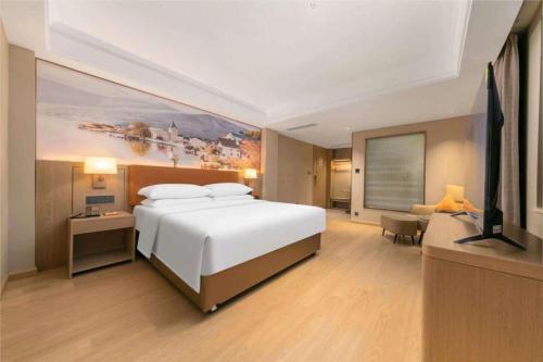 a bedroom with a large bed and a flat screen tv at Vienna Hotel Hubei Jinzhou Changjiang University in Caoshi