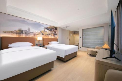 a hotel room with two beds and a flat screen tv at Vienna Hotel Hubei Jinzhou Changjiang University in Caoshi