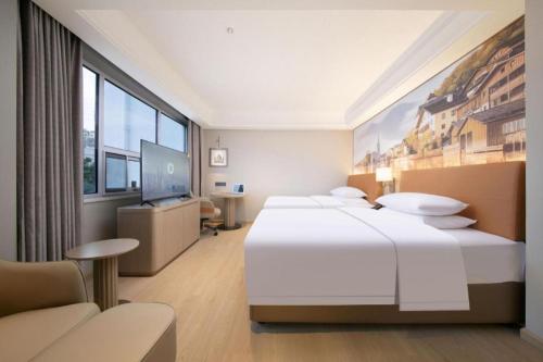 a hotel room with two beds and a flat screen tv at Vienna Hotel Hubei Jinzhou Changjiang University in Caoshi