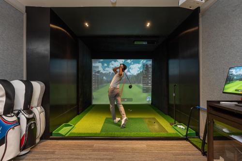 a man playing a golf game on a tv screen at Staybridge Suites Bangkok Sukhumvit by IHG in Bangkok