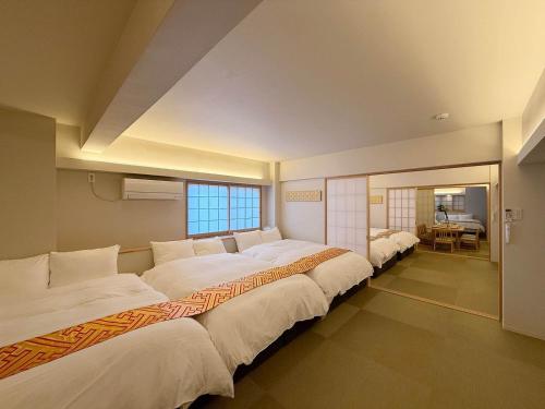 a bedroom with two beds and a dining room at b hotel Miyajima Omotesando - Sacred Island Stay 22 in Miyajima