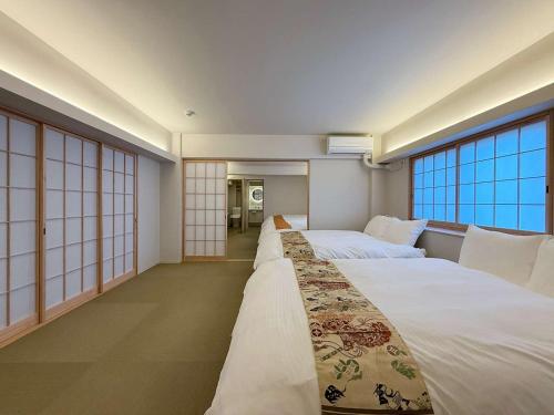 a hotel room with two beds and large windows at b hotel Miyajima Omotesando - Sacred Island Stay 22 in Miyajima