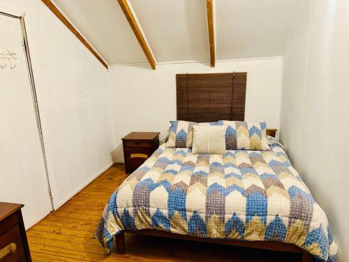 a bedroom with a bed with a quilt on it at Cabaña del Bosque de Laguna Verde in Valparaíso