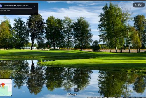 a view of a golf course with a reflection in the water at Guest suite in Richmond in Richmond