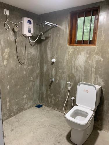 a bathroom with a toilet and a window at Surf Front in Ahangama