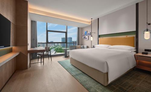 a hotel room with a large bed and a desk at Doubletree By Hilton Zhengzhou East in Zhengzhou