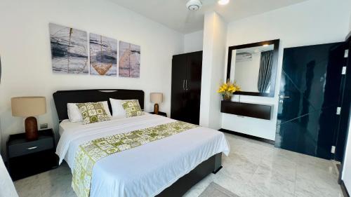 a bedroom with a large white bed and a mirror at M8 Ocean King Three Bed Apartment in Cinnamon Gardens