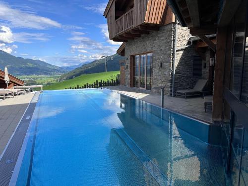 a large swimming pool next to a building with mountains at ZAGLGUT HOTEL-CHALETS Wellness & Views with Summer Card Included in Kaprun