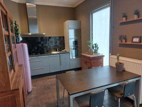 a kitchen with a wooden table and a refrigerator at Huis aan Puyenbroeck in Wachtebeke