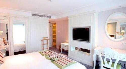 a white room with a bed and a tv at Xiamen Jingmin Central Hotel in Xiamen