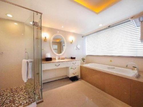 a bathroom with a tub and a sink and a mirror at Xiamen Jingmin Central Hotel in Xiamen