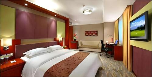 a bedroom with a large bed and a television at Xiamen Jingmin Central Hotel in Xiamen